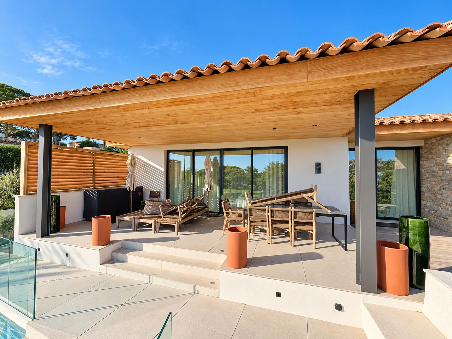 Baies vitrées ouvrant sur la terrasse d’une villa avec piscine.