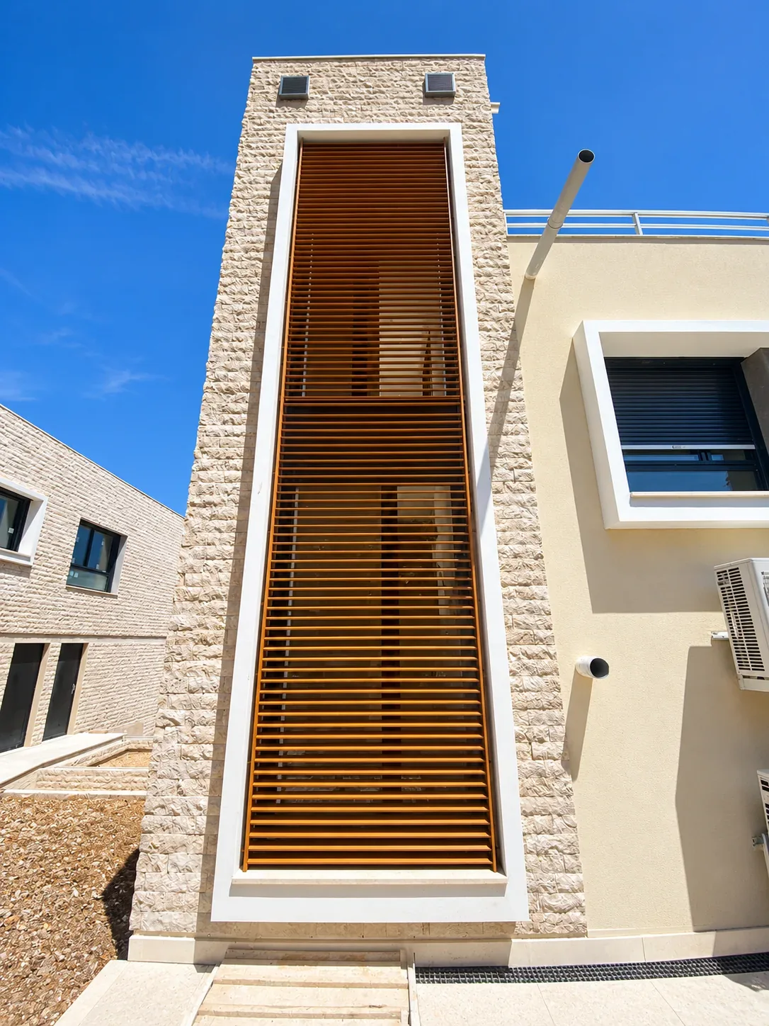 Brise-soleil à lames horizontales dans un encadrement de façade en pierre claire.