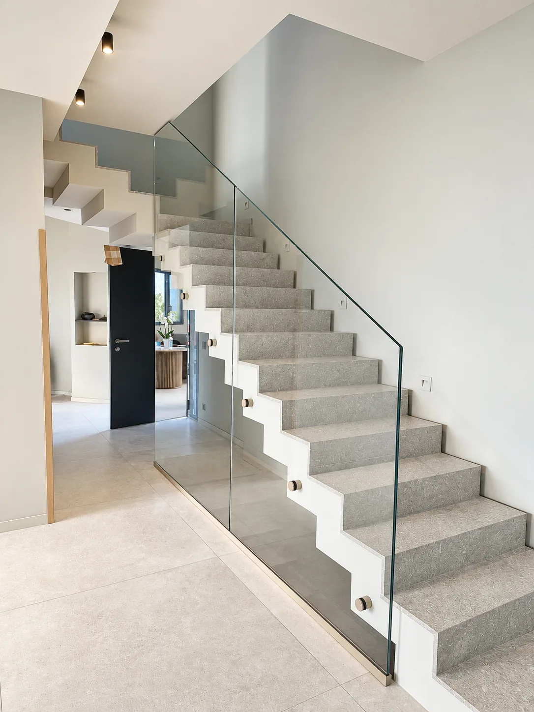Garde-corps en verre accompagnant un escalier intérieur gris.